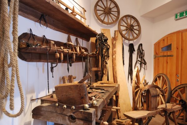 Pracownia stolarza, drewniane koła na ścianie oraz narzędzia do naprawy wozów - Skansen w Sierpcu