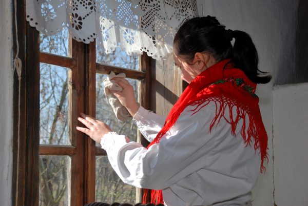 kobieta myje okna w wiejskiej chacie