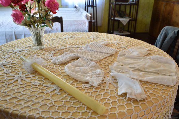 Widok na świecę oraz ubranko do chrztu na stoliku, wystawa - skansen w Sierpcu