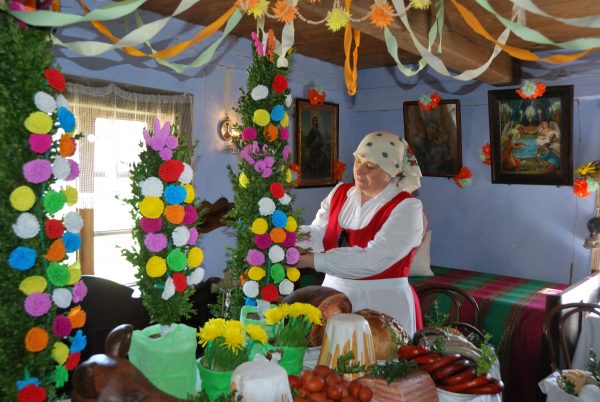 Kobieta w stroju ludowym dekoruje palmy w chacie - skansen w Sierpcu