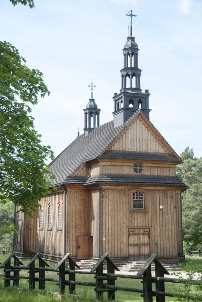 drewniany kościół w otoczeniu drzew po lewej stronie